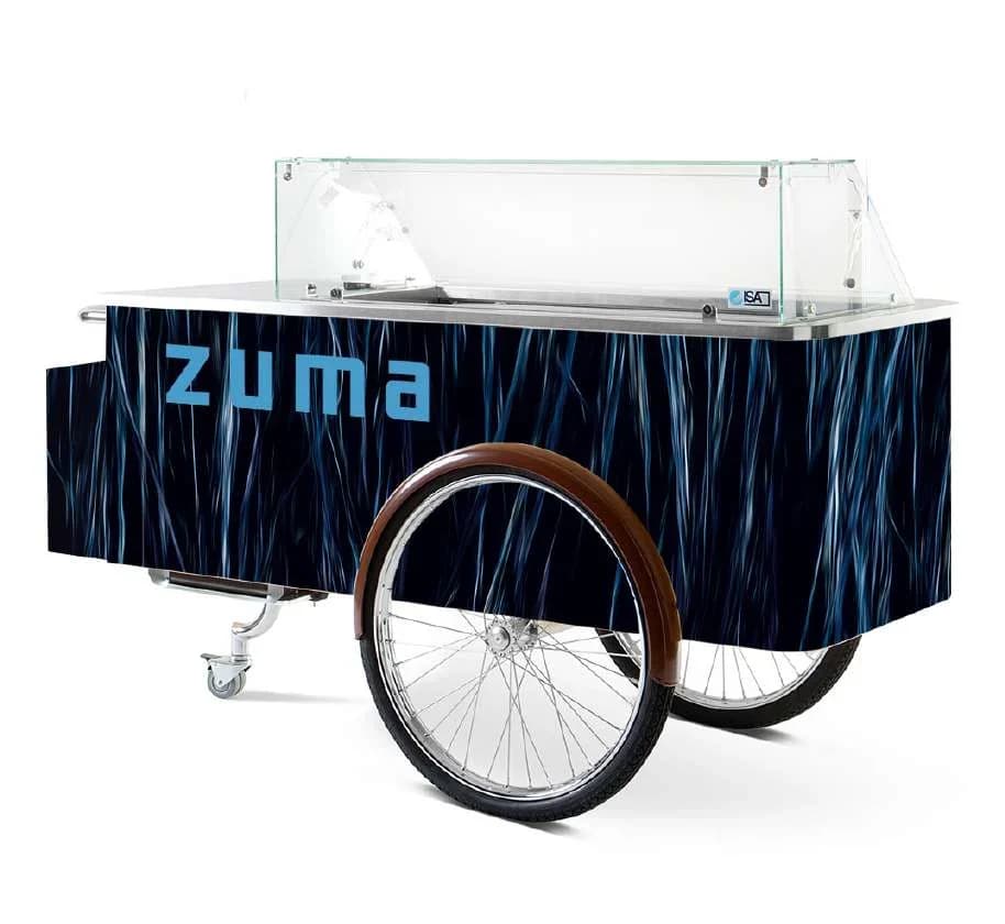 Dark blue Gelato-Go gelato cart branded ZUMA, with a glass display case and a wooden-rimmed wheel
