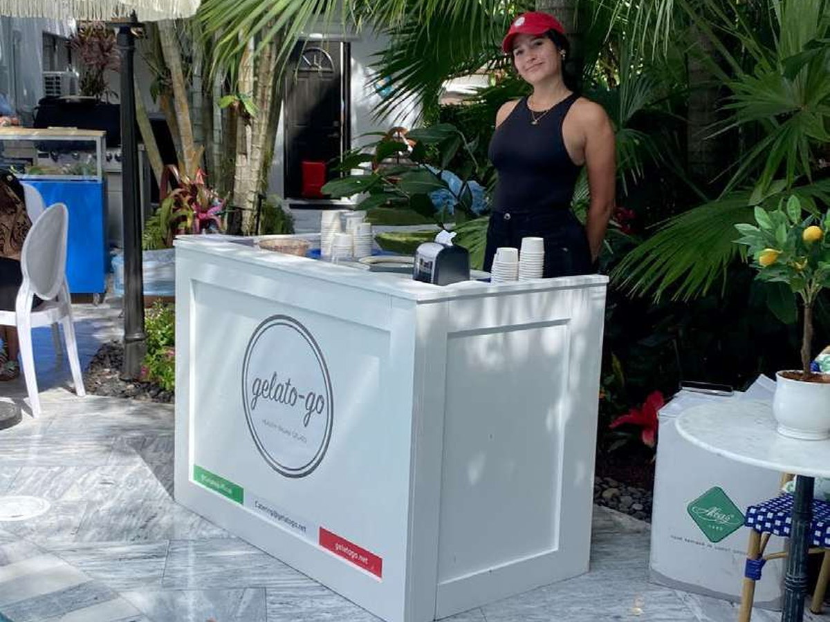 The Counter — the white branded Gelato Go counter staffed by a server at a poolside tropical garden event