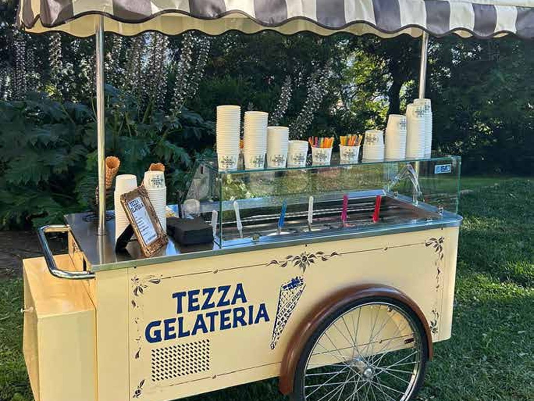 The Vintage Cart — the cream vintage Gelato Go cart with striped awning, glass gelato display and spoked wheel, on a garden lawn
