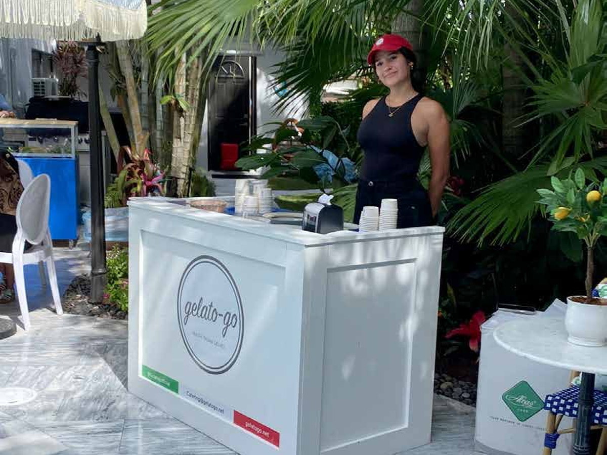 The White Counter — the white branded Gelato Go counter staffed by a server on a marble patio framed by palms